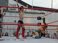 building crew_cut crowd fight pose:kneeling pose:standing pose:two_arms_up shirtless short_hair sport squared_circle subject:human type:photograph wrestler wrestling // 2667x2000 // 723KB