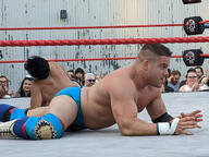 crew_cut crowd fight pose:belly_down pose:laying shirtless short_hair sport squared_circle subject:human tagme type:photograph wrestler wrestling // 2667x2000 // 576KB
