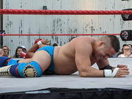 crew_cut crowd fight pose:belly_down pose:laying shirtless short_hair sport squared_circle subject:human type:photograph wrestler wrestling // 2667x2000 // 574KB